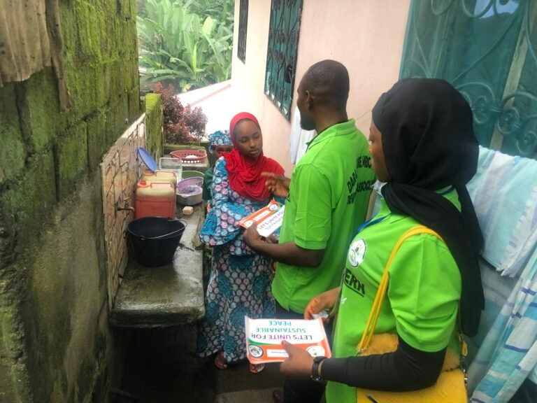 Outreach workers speak with a seated resident outside a home.