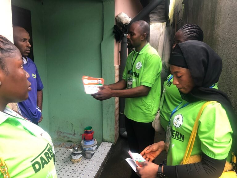 Outreach workers share printed information with residents at a doorway.