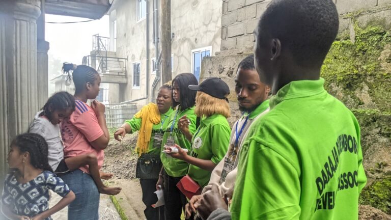 DAREM outreach workers speak with residents along a path between homes.