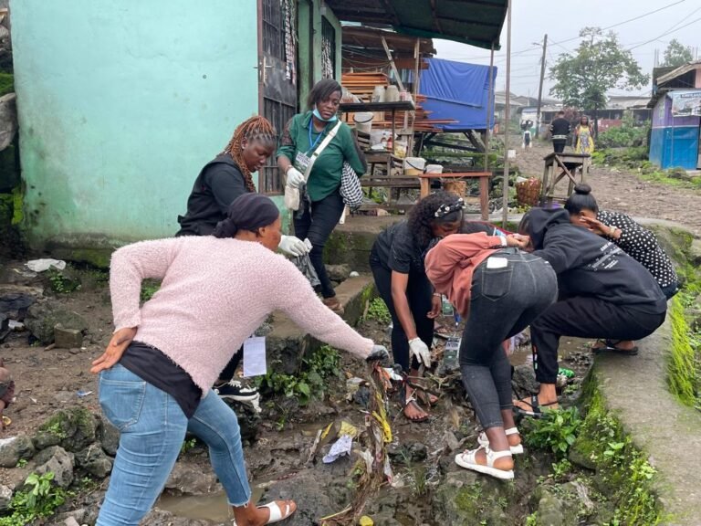 Volunteers remove litter and debris from a drainage channel near homes.