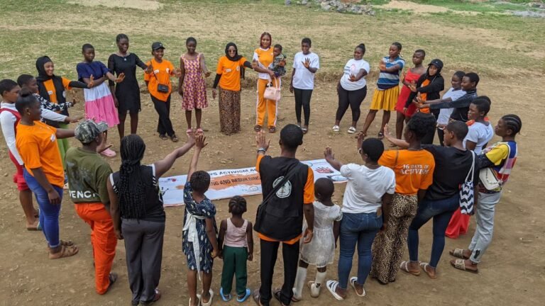 Participants gather in a circle on a grassy field for a group activity.