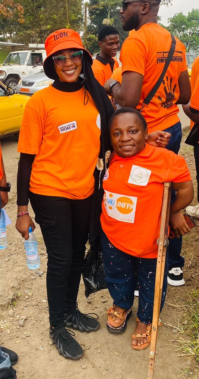 Two campaign participants in orange shirts pose together outdoors.