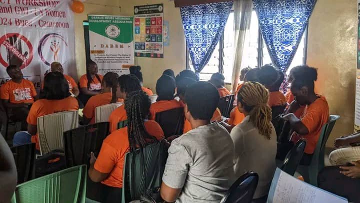 Participants attend an indoor discussion beside campaign posters.