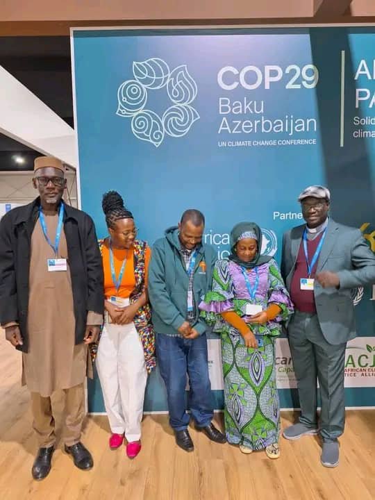 Delegates pose together in front of a COP29 conference display.