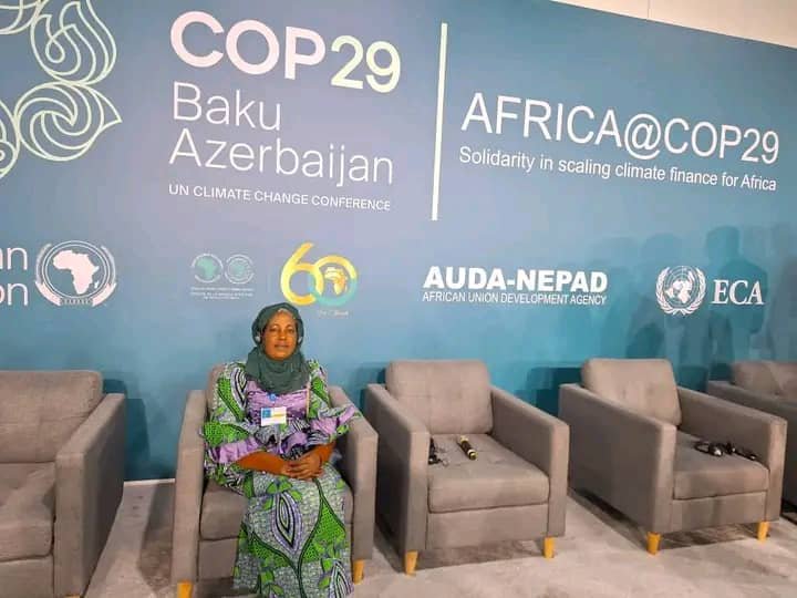 An attendee sits beside a COP29 Africa pavilion backdrop.
