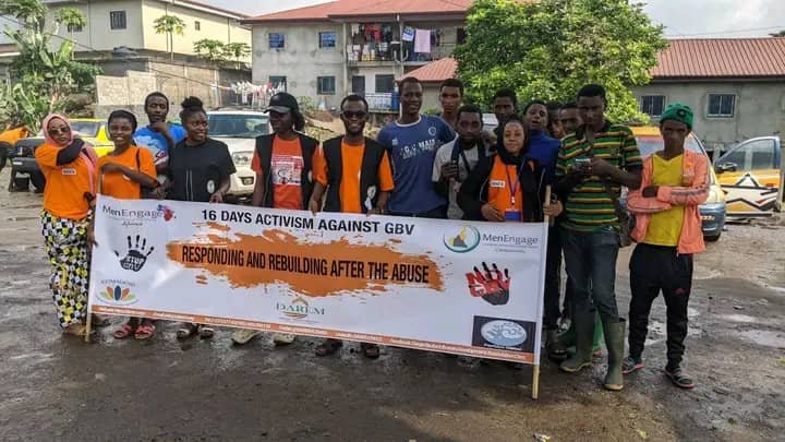 Campaign participants pose outdoors behind a 16 Days of Activism banner.