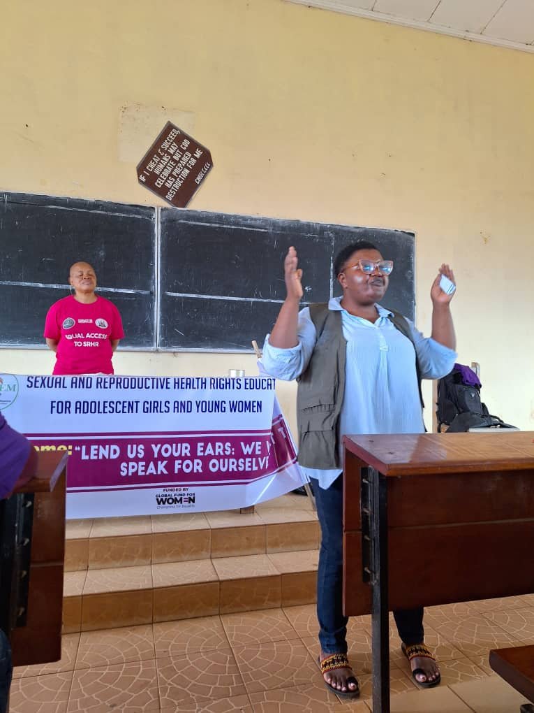 A facilitator raises a hand while addressing a classroom workshop.